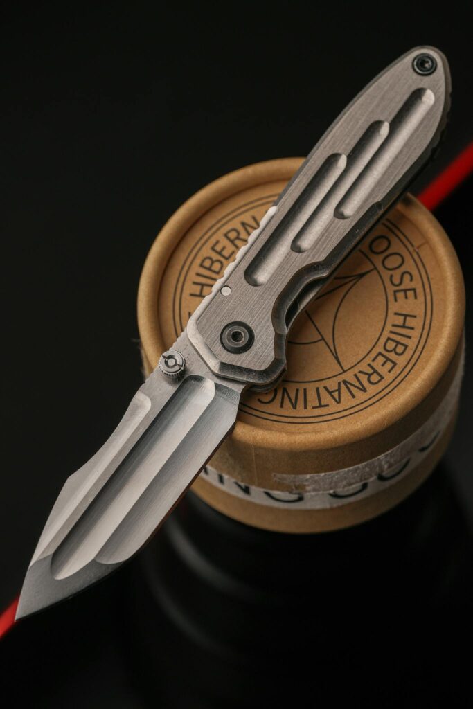 Elegant close-up of a modern folding knife resting atop a circular object, showcasing craftsmanship.